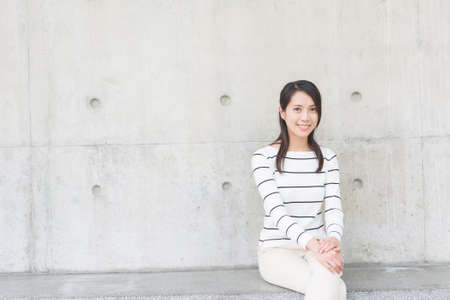 asian young woman sit with copyspace on wallの写真素材
