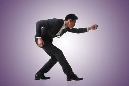 Asian business man posing tug of war, full length portrait isolatedの写真素材