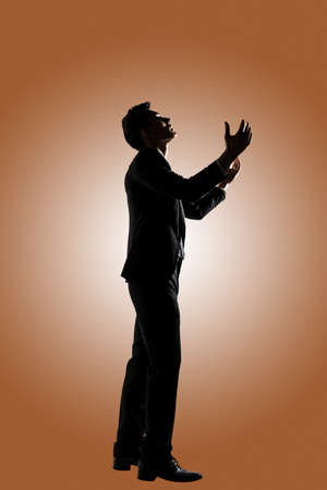 Silhouette of Asian businessman praying, full length portrait isolatedの写真素材