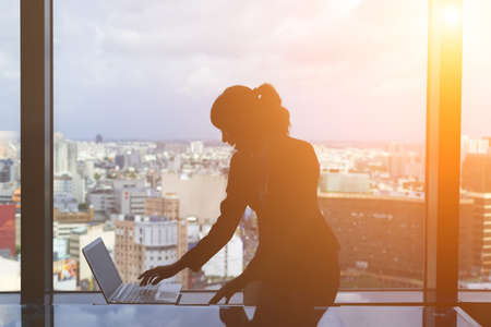 Silhouette of businesswoman work near window in hotel room.の写真素材