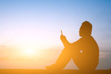 silhouette of one man use cellphone in the outsideの写真素材