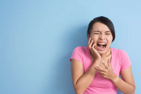 Asian young woman feel hurt with hypersensitive teeth,  closeup portrait with copyspace