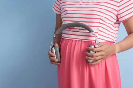 Asian young pregnant put earphones on her belly. Concept of prenatal education.の写真素材