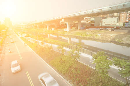 City traffic with cars motion blurred on road near bridge on river in daytime in Taipei, Taiwan, Asia.の写真素材