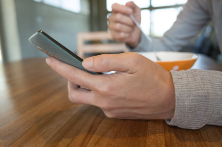 woman eat cereal with milk when using smartphoneの写真素材