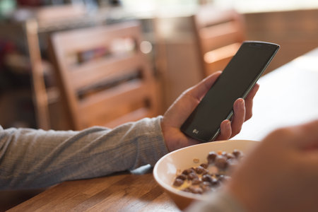 woman eat cereal with milk when using smartphone