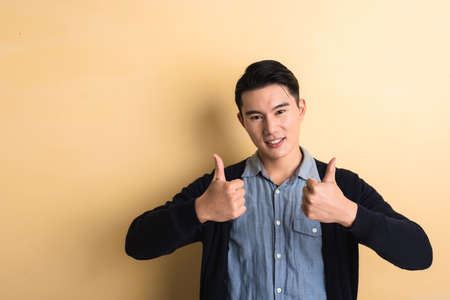 young man give you a gesture of good, shot at studio yellow backgroundの写真素材