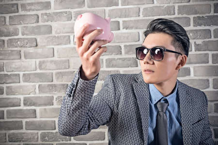 greedy businessman look at the pink pig bankの写真素材