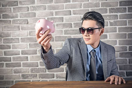 greedy businessman look at the pink pig bankの写真素材