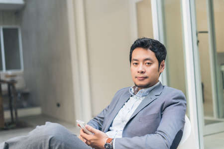 asian business man sit and using smartphone in the outdoorの写真素材