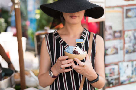 asian woman hold a coconut ice at Chatuchak weekend market, Bangkok, Thailandの写真素材