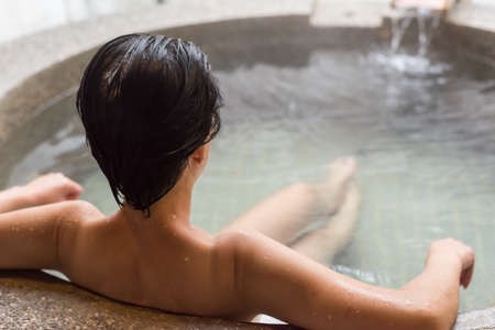 rear view of asian mature woman at the hot spring poolの写真素材