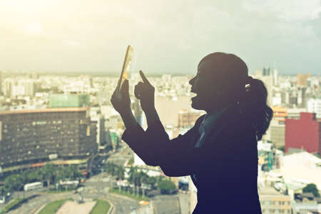 Silhouette of Asian business woman using tablet in a room, concept of technology or communication.の写真素材