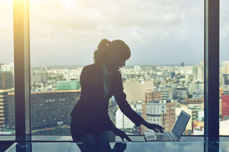 Silhouette of businesswoman work near window in hotel room.の写真素材