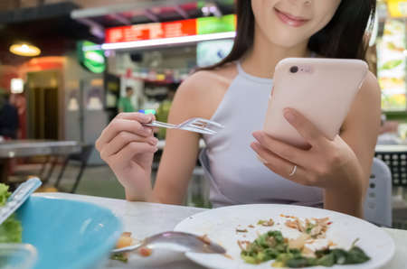 asian young woman read message on cellphone at dinner, bangkok, asiaの写真素材