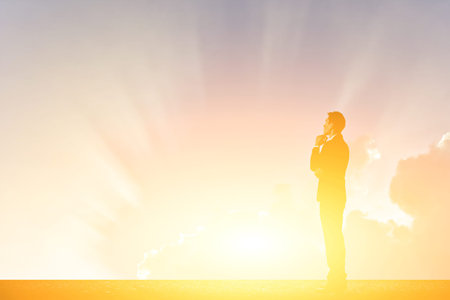 businessman standing against sunset with copyspace on skyの写真素材