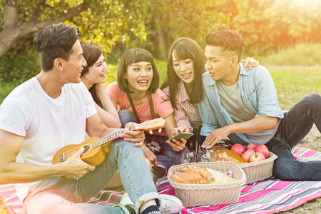 Asian people look something at cellphone with his friends in the parkの写真素材