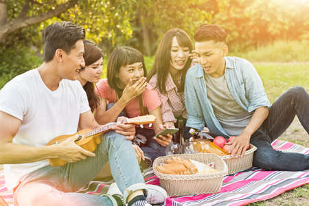 Asian people look something at cellphone with his friends in the parkの写真素材