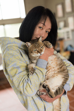 woman holding her old cat in the house