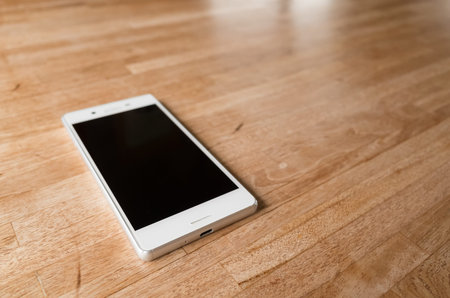 mobile on wooden desk with nobody in the room