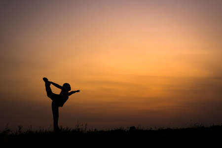 silhouette of young woman with yoga pose in the outdoorの写真素材
