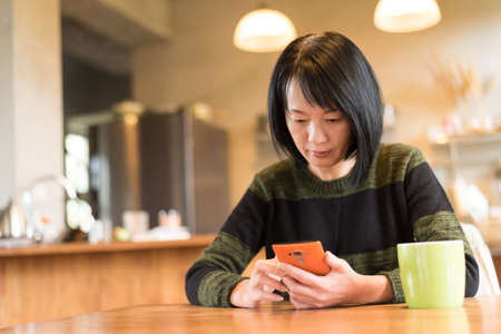 Asian mature woman using smartphone at homeの写真素材