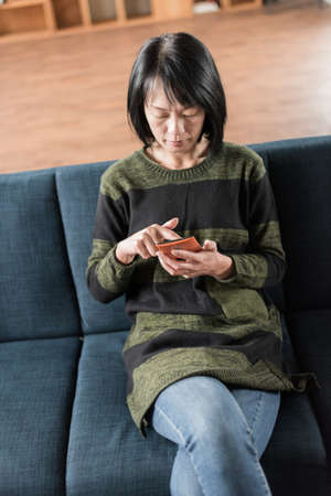 Asian woman using cellphone in the houseの写真素材
