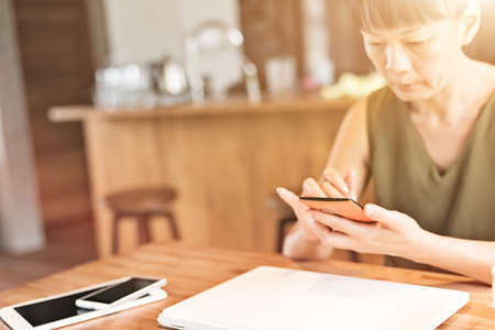 Asian mature woman using smartphone at homeの写真素材