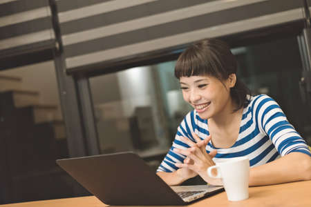 Asian woman using laptop at night, concept of working at homeの写真素材