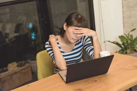 angry Asian young woman using laptop at homeの写真素材