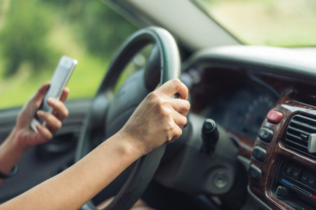 women driver with a cell phone in hand while driving