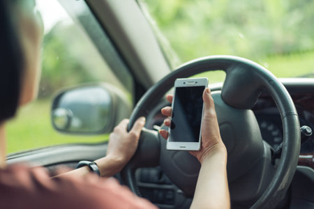 women driver with a cell phone in hand while driving