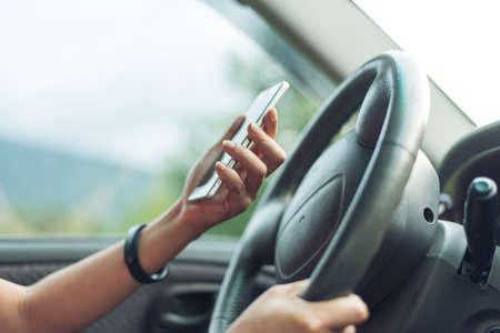 women driver with a cell phone in hand while drivingの写真素材