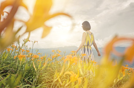 asian woman feel free and stand in the yellow tiger lily farm