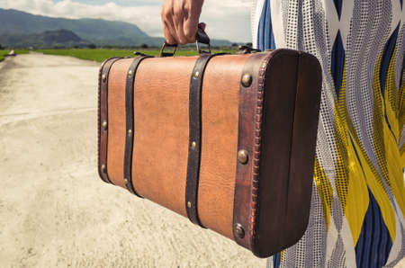 woman holding a suitcase on the road in the countrysideの写真素材