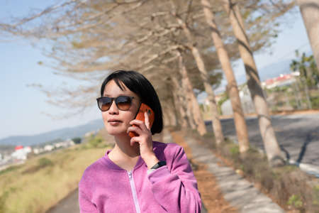 mature Asian woman talk on cellphone in the outdoorの写真素材