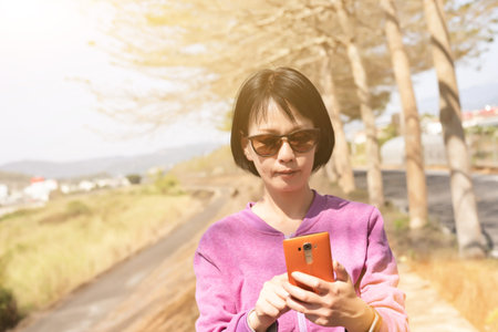 mature Asian woman using the smart phone at outdoor