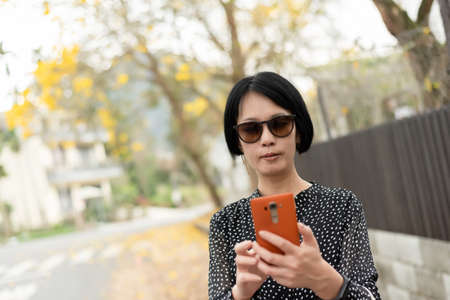 mature Asian woman using mobile phone at outsideの写真素材