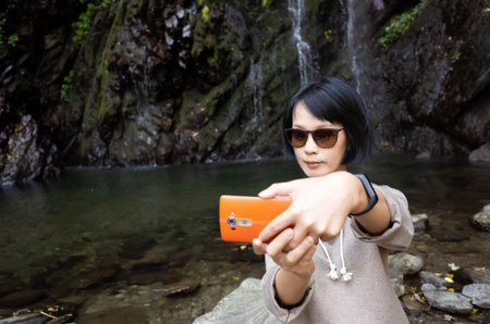 Asian woman selfie near the waterfall at outdoor