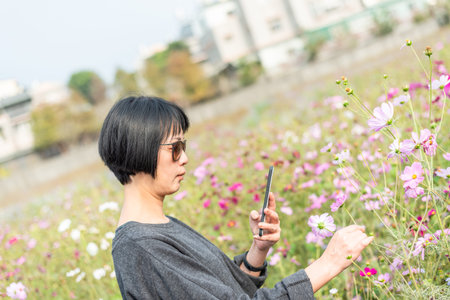 Asian woman take a picture on a flower in the outdoor