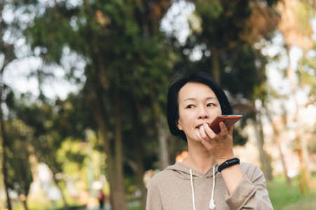 Asian mature woman talk on mobile phone at parkの写真素材