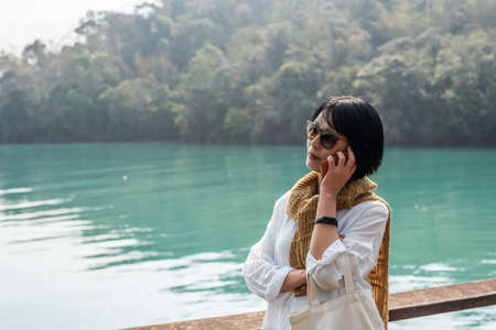 traveling woman talk on mobile near Sun Moon Lake, Nantou, Taiwanの写真素材