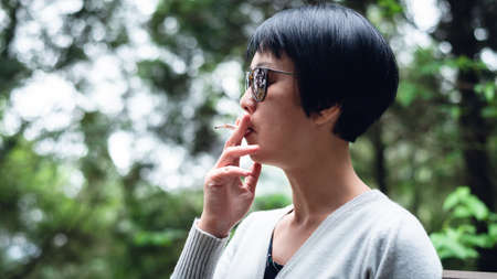 Asian woman smoking in the outdoor forestの写真素材