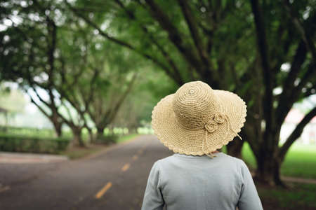Asian woman take a walk on the way under the treesの写真素材