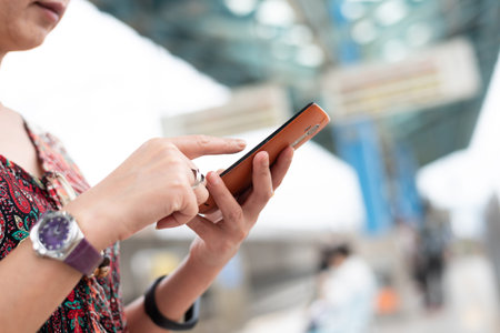mature traveling woman waiting and using a cellphone at a train platform in Taiwan