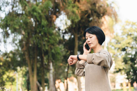 Asian woman talk on cellphone and using smart watchの写真素材