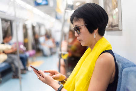 mature Asian woman using smartphone at the MRT carriage with copyspaceの写真素材