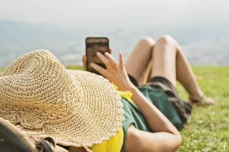 Asian woman lie on grassland and using cellphone