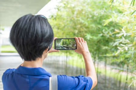 modern Asian woman take a picture by cellphone at a corridorの写真素材