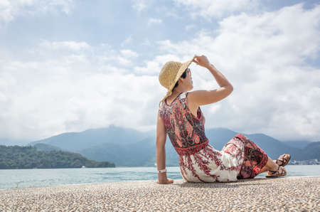 traveling Asian woman with hat sit at a pier at Sun Moon Lake, Taiwanの写真素材